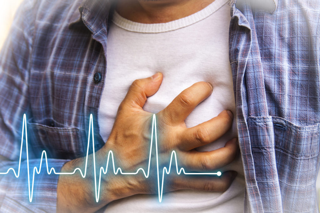 Man holding his chest suffering from a heart attack and heart beat waves shown overtop.